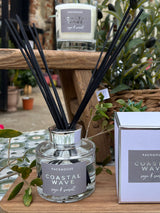 Packhouse Coastal Wave diffuser with reeds on a wooden surface with plants in the background