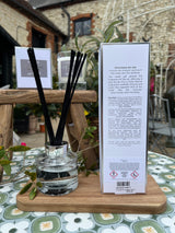 Diffuser with black sticks and packaging on a wooden stand outdoors
