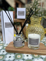 Packhouse Citrus diffuser and candle on a wooden stand with a blurred background