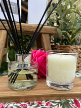 Diffuser with candles and reeds on a wooden stand with plants in the background